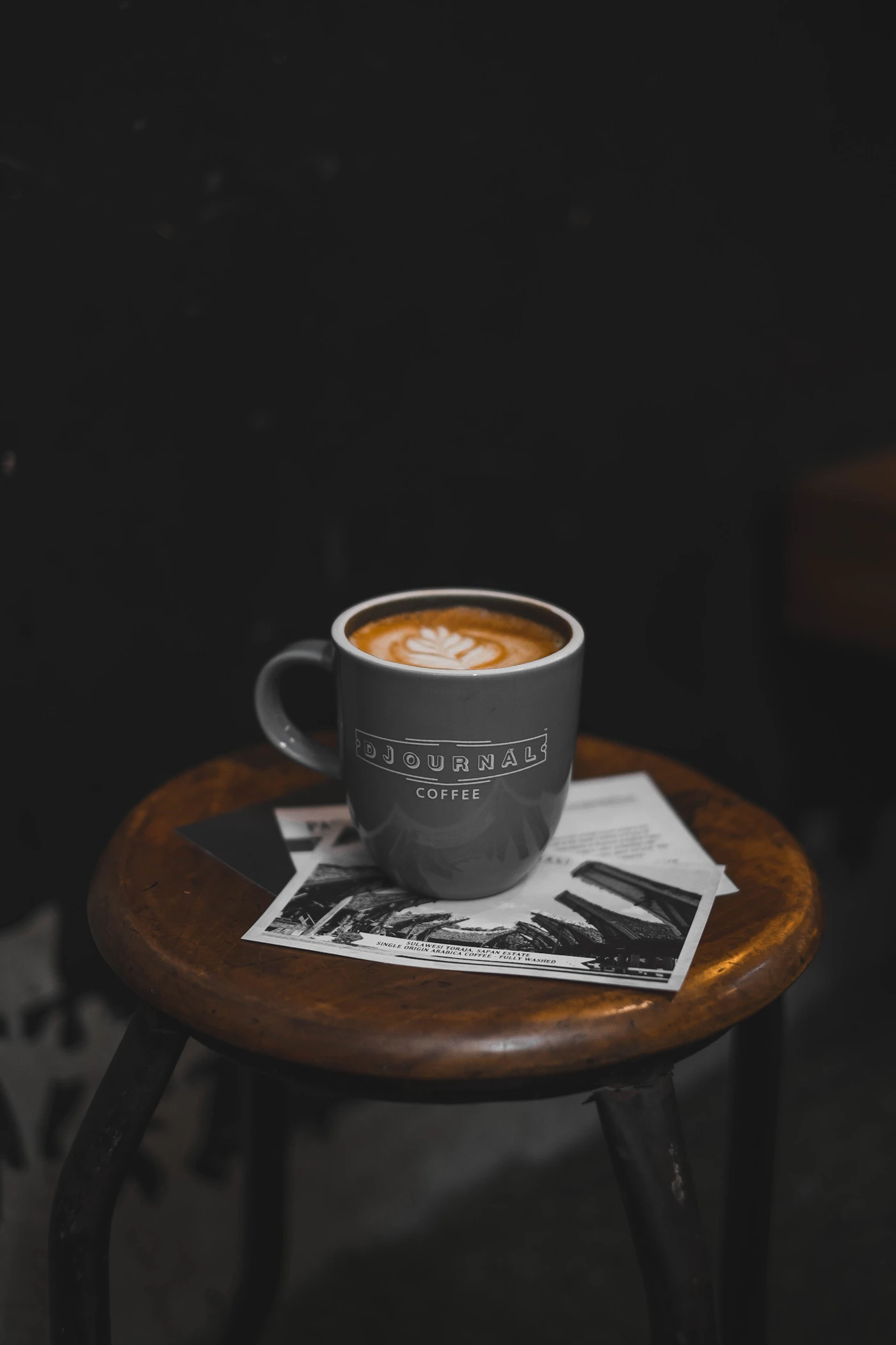 Koyu bir kafede ahşap tabure üzerinde latte